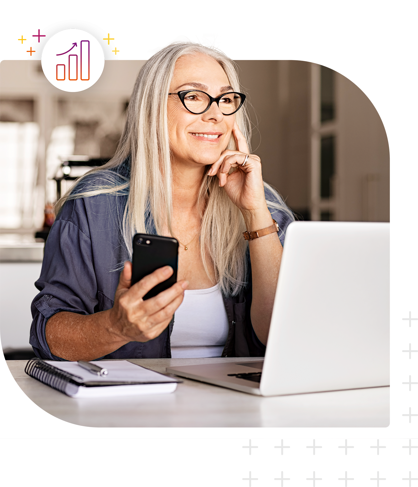 Person sitzt an einem Schreibtisch mit Laptop, Smartphone und Notizbuch.