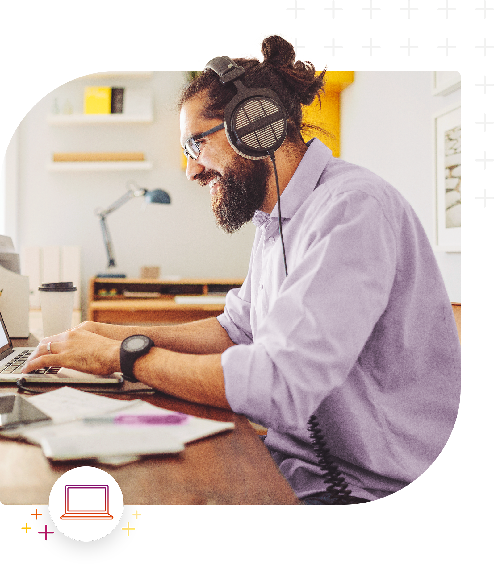 Person mit Bart und Brille sitzt konzentriert am Schreibtisch mit Laptop und Kopfhörern