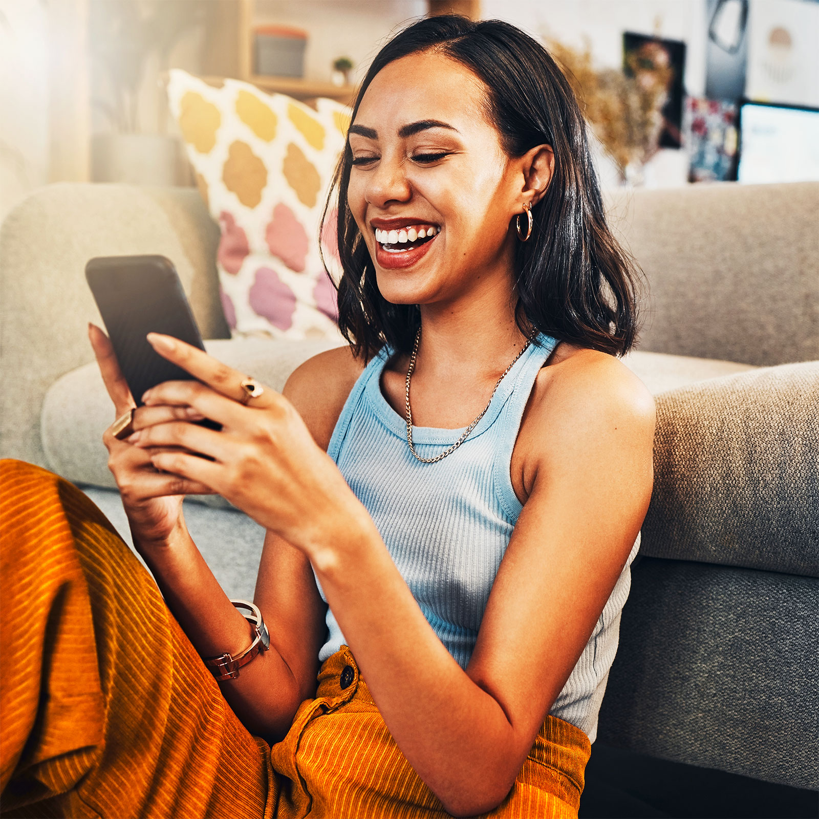 Lächelnde Person sitzt entspannt und benutzt ein Smartphone