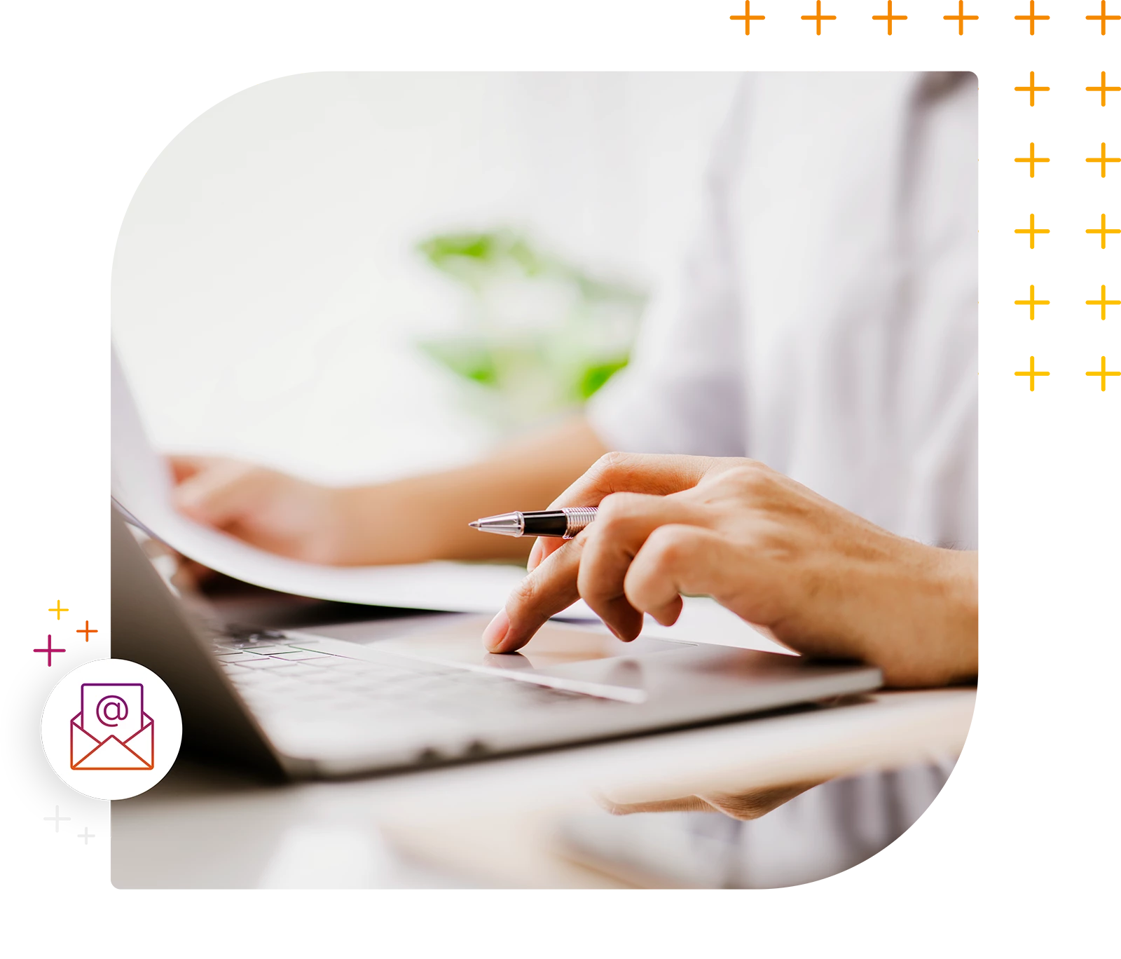 Hände einer Person mit Stift beim Arbeiten an einem Laptop und Papieren